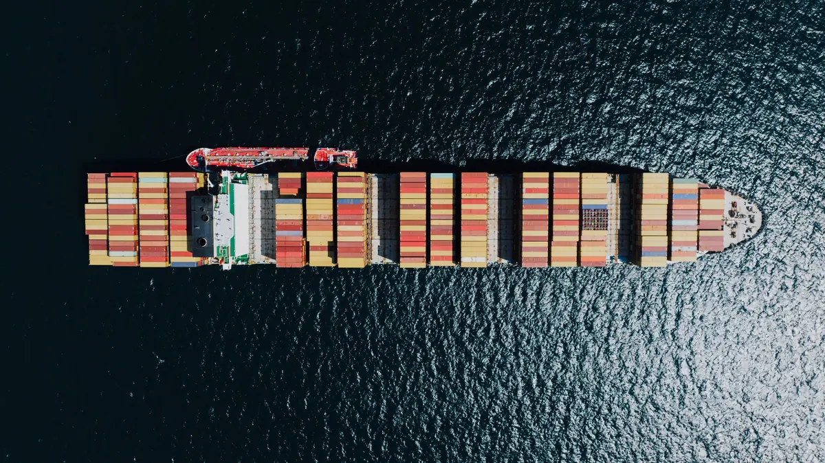 Container ship loaded with stacked containers, seen from directly above at sea (stock photo)